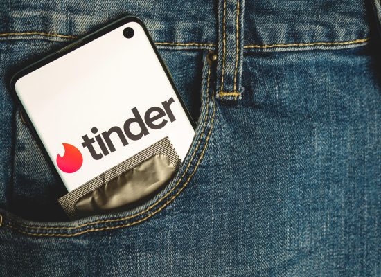 Tinder,App,Logo,On,Smartphone,With,With,Condom,In,Blue